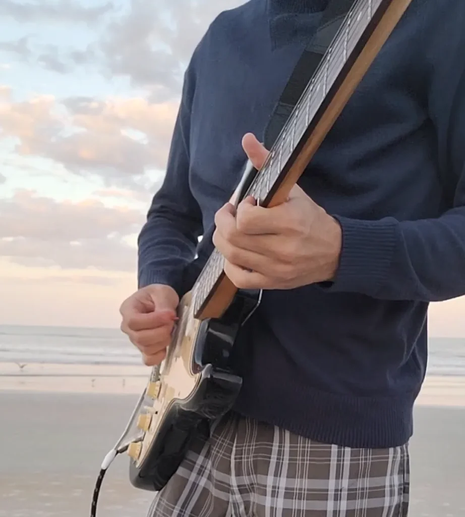 Beach music producer with Strat guitar and looper pedal for live loop building online music lessons and guitar tutorials