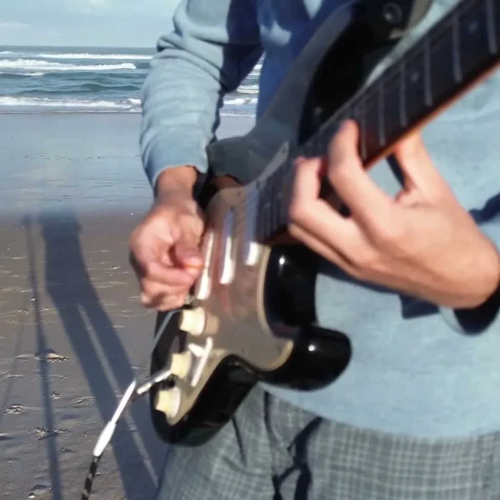 Live looping guitarist playing Save The Population at the beach