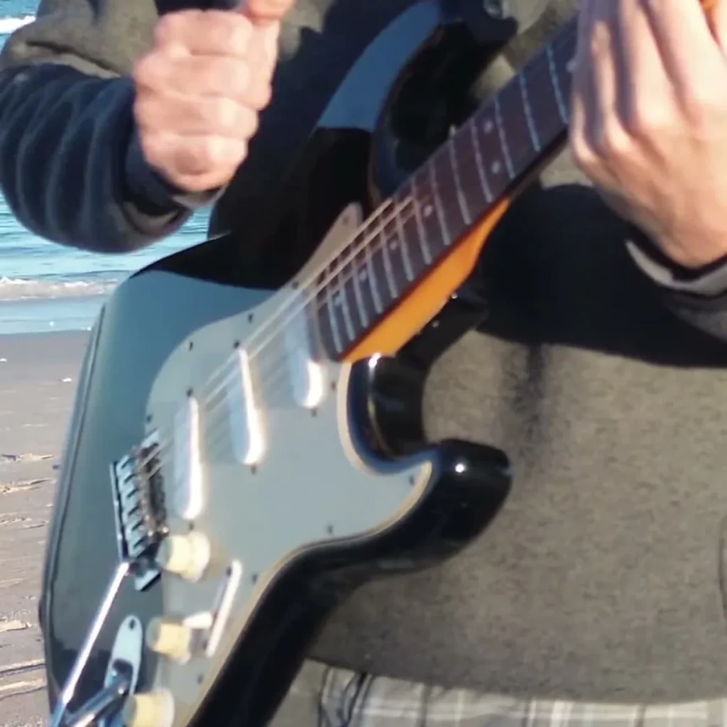 Guitarist at the beach capturing a Bad Love Guitar Loop session