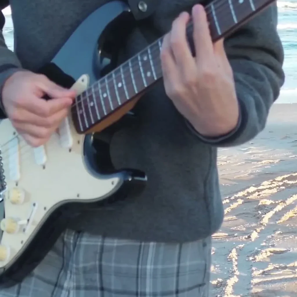 Guitarist playing Take Me Out Guitar Loop by the ocean